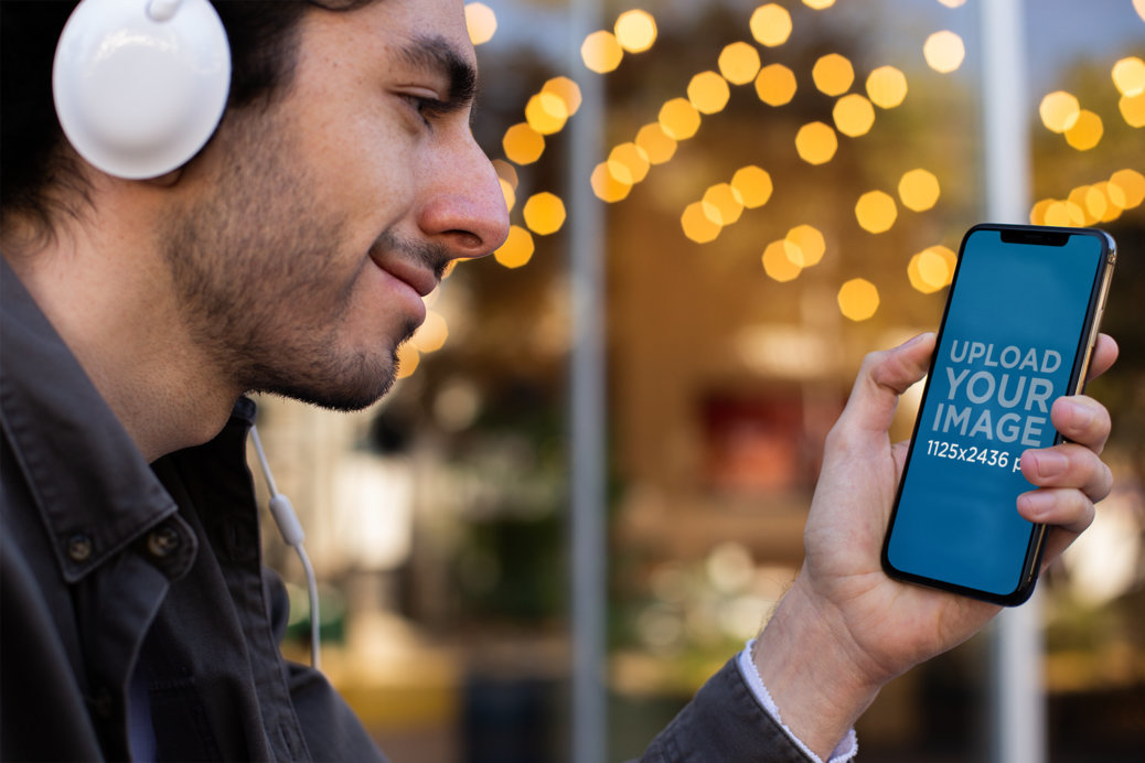 Mockup of a Man Holding His iPhone 11 Pro While Listening to a Podcast