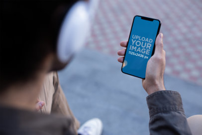 Mockup for a Podcast with a Man Wearing Headphones and Holding an iPhone XS Max 24811