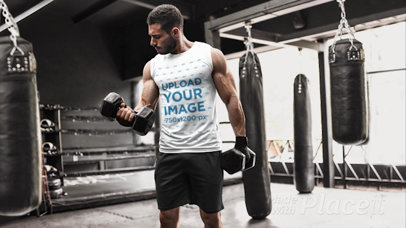 Parallax Video of a Muscled Man in a Sleeveless Shirt Lifting Weights at a Boxing Gym