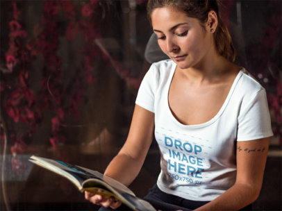 T-Shirt Mockup Featuring a Woman Reading a Magazine