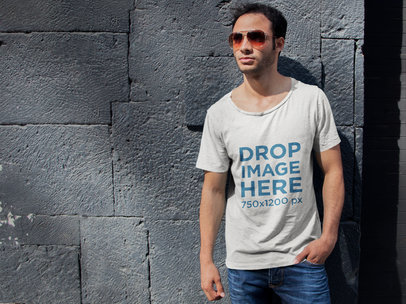 T-Shirt Mockup of a Young Man Leaning on a Stone Wall