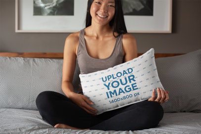 Pillow Mockup Featuring a Woman Sitting Cross-Legged on Her Bed 