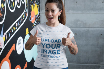 T-Shirt Mockup of a Happy Customer Giving Thumbs up Against a Graffiti Wall