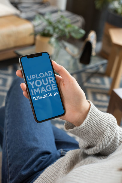 Mockup Featuring an iPhone XS Being Held by a Woman Sitting Down 25356