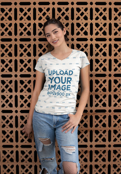Mockup of a Woman Posing with a V-Neck T-Shirt Against a Patterned Wall