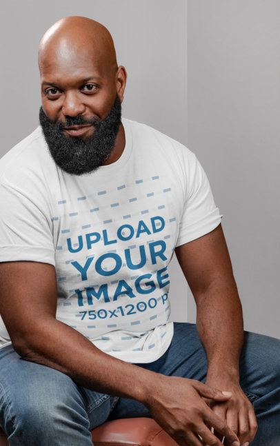T-Shirt Mockup of a Bald Bearded Man Sitting on a Chair 21526