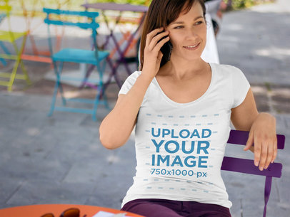 T-Shirt Mockup of a Woman Sitting at an Outdoor Table