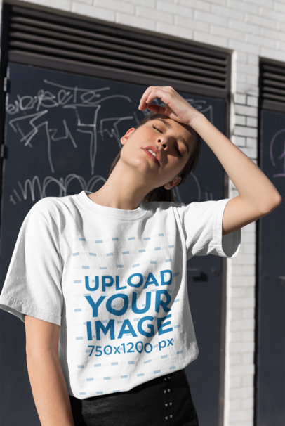 T-Shirt Mockup of a Woman Posing in Front of a Graffiti