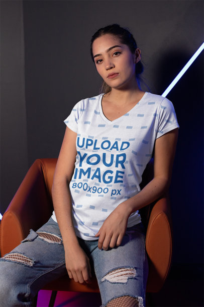 Mockup of a Woman Wearing a V-Neck Tee and Ripped Jeans in a Dark Room