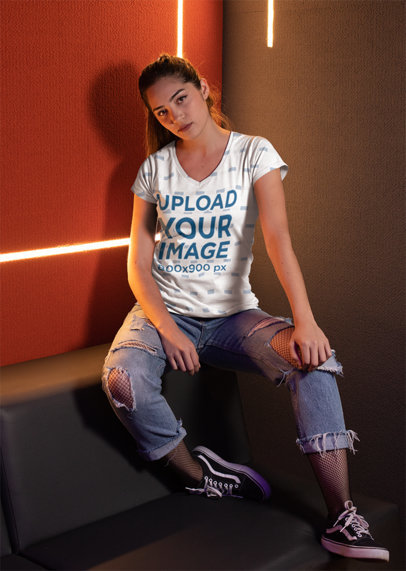 V-Neck Tee Mockup of a Woman Sitting Against Cool Led Lights