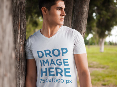 T-Shirt Mockup of a Young Man Leaning Against a Tree
