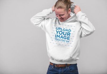 Mockup of a Blonde Man Putting on His Pull-Over Hoodie in a Studio 23085
