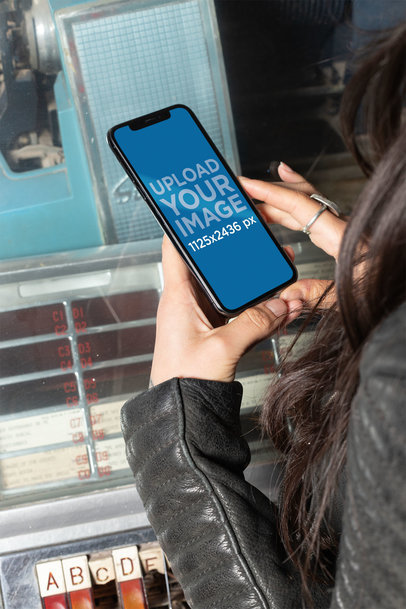 Mockup of a Girl Using Her iPhone XS Next to a Jukebox 25383