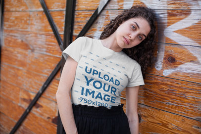 Tee Mockup of a Pretty Girl with Big Blue Eyes Leaning on a Wooden Wall 25795