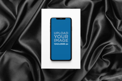 iPhone 11 Pro Max Mockup over a Cardboard Surrounded by a Dark Fabric