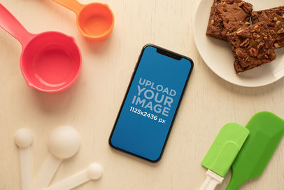 Mockup of an iPhone XS Surrounded by Baking Supplies 25490