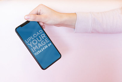 Mockup of a Girl Holding an iPhone XS by the Upper Corner 25437