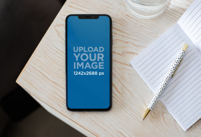 iPhone 11 Pro Max Mockup Next to an Open Notebook over a Wooden Surface