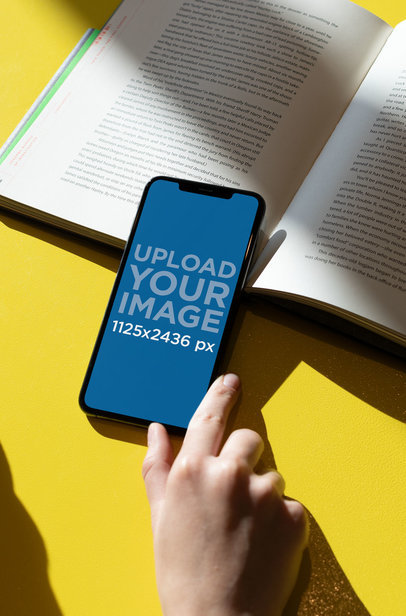 iPhone XS Mockup over an Open Book 25442