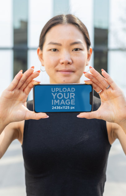 Mockup of an iPhone 11 Pro in the Hands of a Serious Looking Woman 