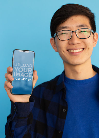iPhone 11 Pro Mockup Featuring a Smiling Man with Glasses Against a Blue Surface
