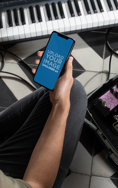 iPhone 11 Pro Max Mockup Featuring a Man Inside His Home Studio