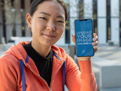 Mockup of a Sporty Woman with Tied Hair Holding Her iPhone 11 Pro Max