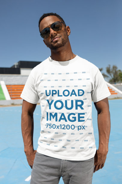 T-Shirt Mockup of a Muscled Man Wearing Sunglasses in a Sports Field