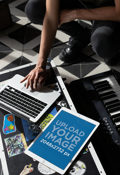 iPad Pro Mockup Featuring a Man Checking His Laptop at His Home Studio