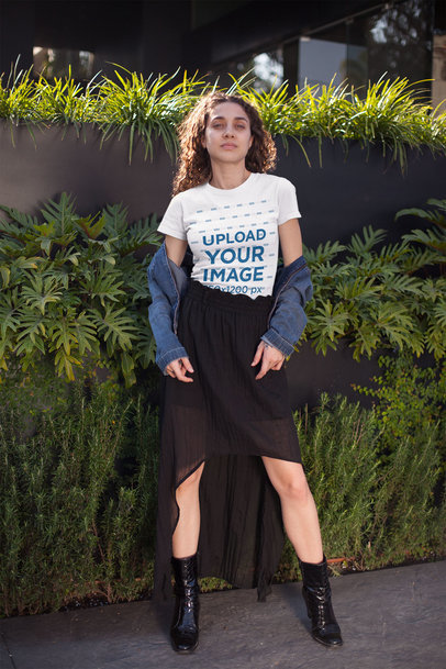 Tee Mockup of an Audacious Curly-Haired Woman Standing in Front of Street Plants