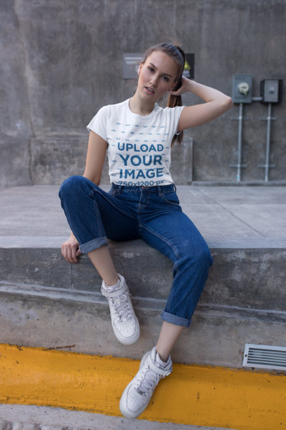 T-Shirt Mockup of a Cute Woman with Denim Urban Style Sitting on the Sidewalk