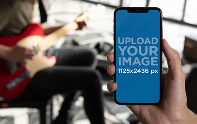 iPhone 11 Pro Mockup Featuring a Man Playing Guitar in a Home Studio