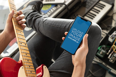 Mockup of a Man Watching His iPhone 11 Pro Max While Playing Guitar 