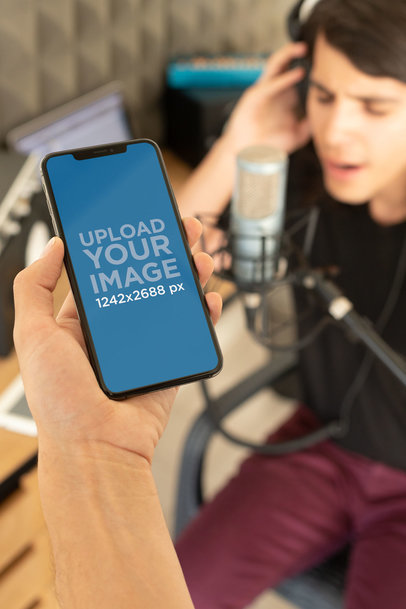 iPhone XS Max Mockup Featuring a Man Recording at a Home Studio 25756