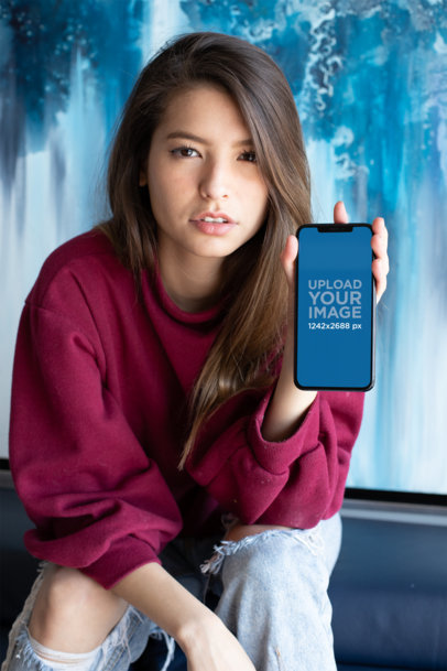 iPhone 11 Pro Max Mockup Of a Woman in Ripped Jeans Against a Blue Marble Wall