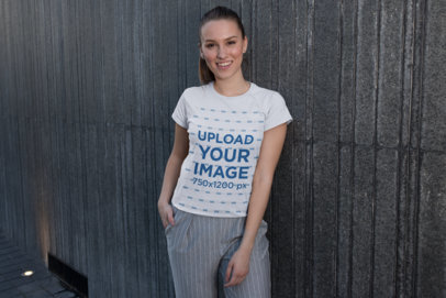 Tee Mockup Featuring a Smiling Woman Posing by Facade Panels