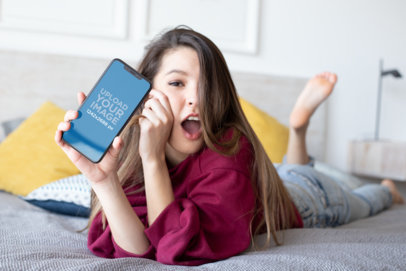 iPhone 11 Pro Max Mockup of an Amazed Woman Lying on Her Bed