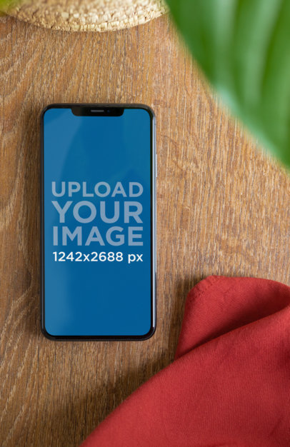 iPhone XS Max Mockup Next to a Cloth Napkin over a Wooden Table 25889