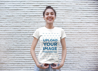 T-Shirt Mockup of a Smiley Woman Standing in Front of a White Brick Wall