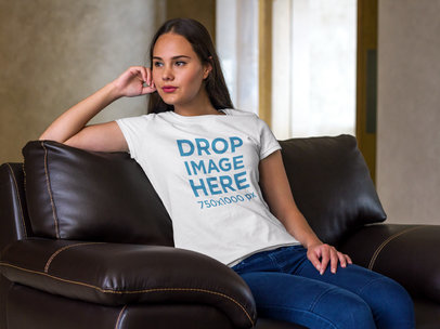 T-Shirt Mockup of a Young Woman Sitting on a Sofa 