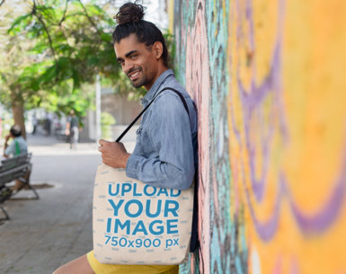  Tote Bag Mockup of a Man with a Hairbun Standing By a Colorful Wall 