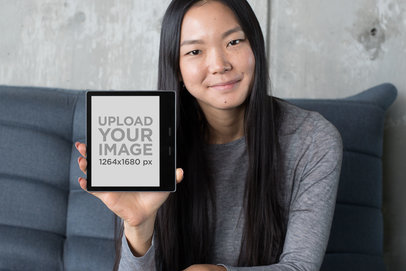 Kindle Oasis Mockup of a Long-Haired Woman Sitting on a Sofa