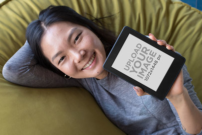 Kindle Paperwhite Mockup of a Smiling Woman Lying over a Pillow