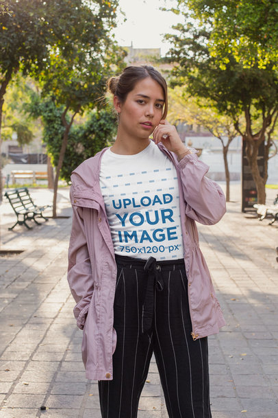 T-Shirt Mockup of a Woman in a Trenchcoat Posing at a Park 26870