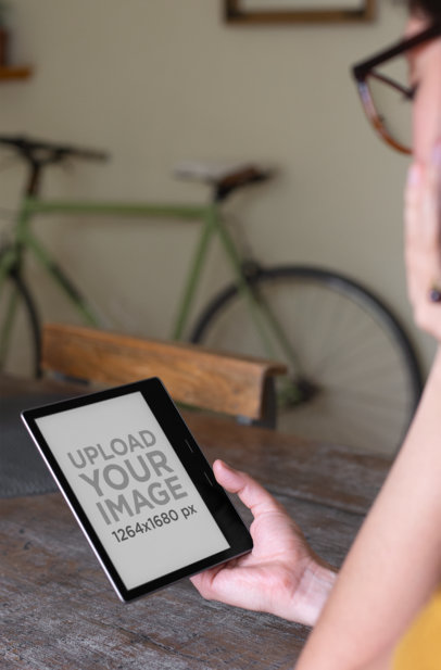 Over-The-Shoulder Mockup of a Woman Reading from Her Kindle Oasis at Her Home