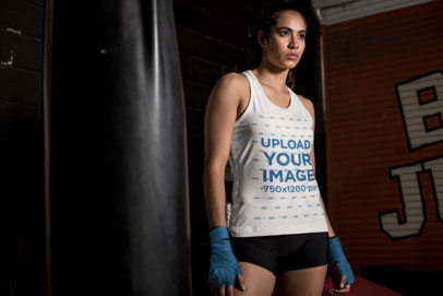 Tank Top Mockup of a Female MMA Fighter Standing by a Punching Bag