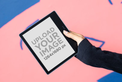 Mockup of a Woman Holding a Kindle Oasis Mockup Against a Colorful Surface