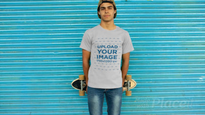 T-Shirt Video of a Young Man Holding a Skateboard Behind His Back