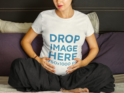 T-Shirt Mockup of a Pregnant Lady Sitting on a Bed