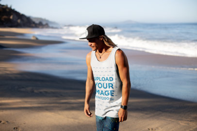 Tank Top Mockup of a Blonde Long-Haired Man with a Cap by the Beach